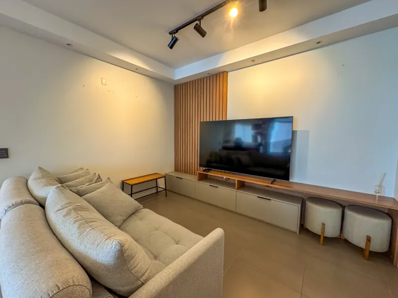 Sala de TV com painel ripado em madeira e sofá amplo