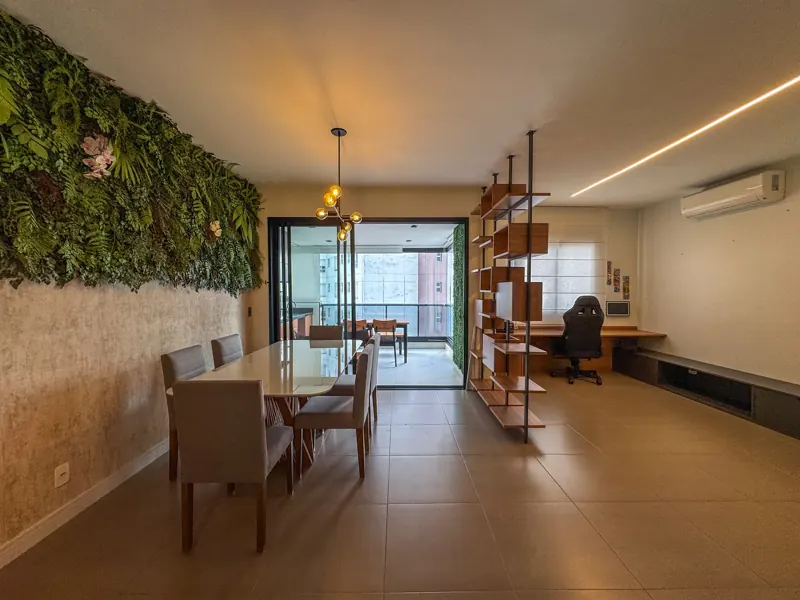 Ambientes integrados com jardim vertical, mesa de jantar e escritório ao fundo