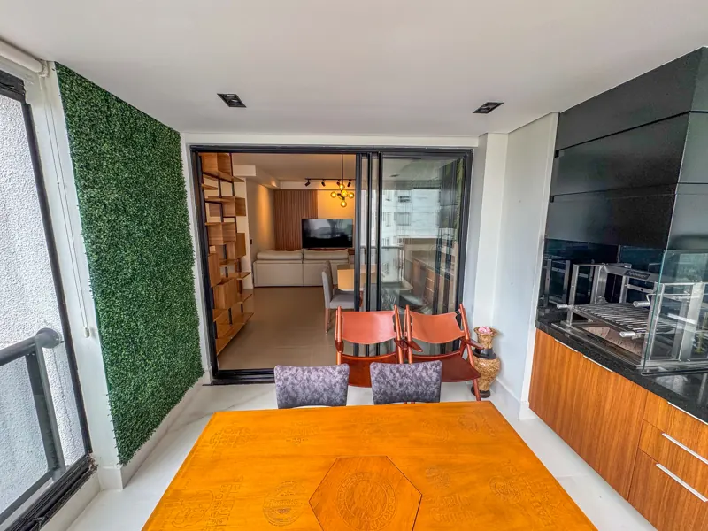Varanda gourmet com jardim vertical, mesa e churrasqueira