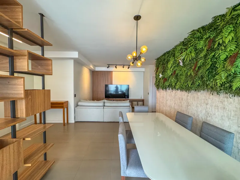 Mesa de jantar branca, estante planejada em madeira e jardim vertical