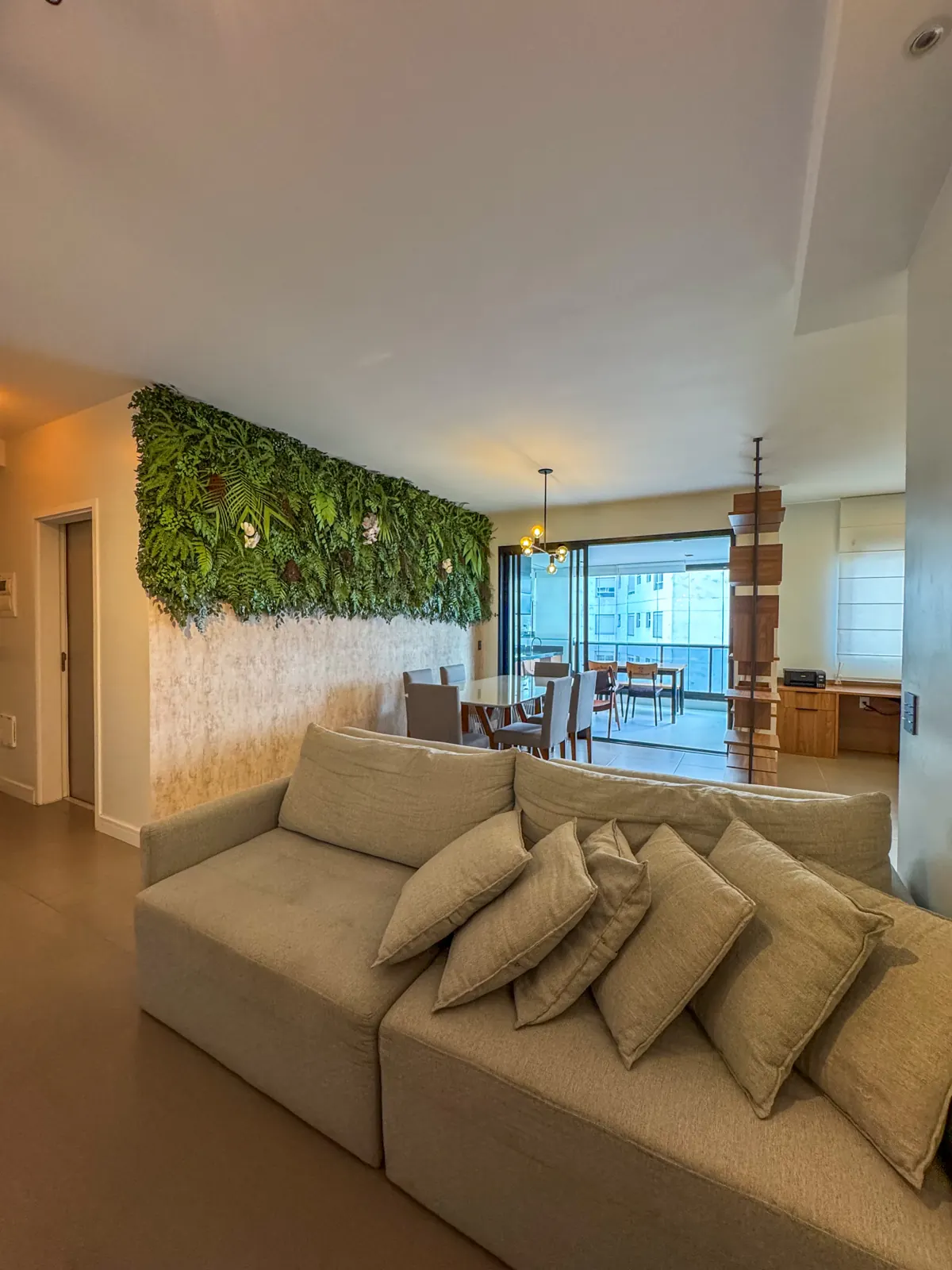 Sala de estar com sofá claro e jardim vertical