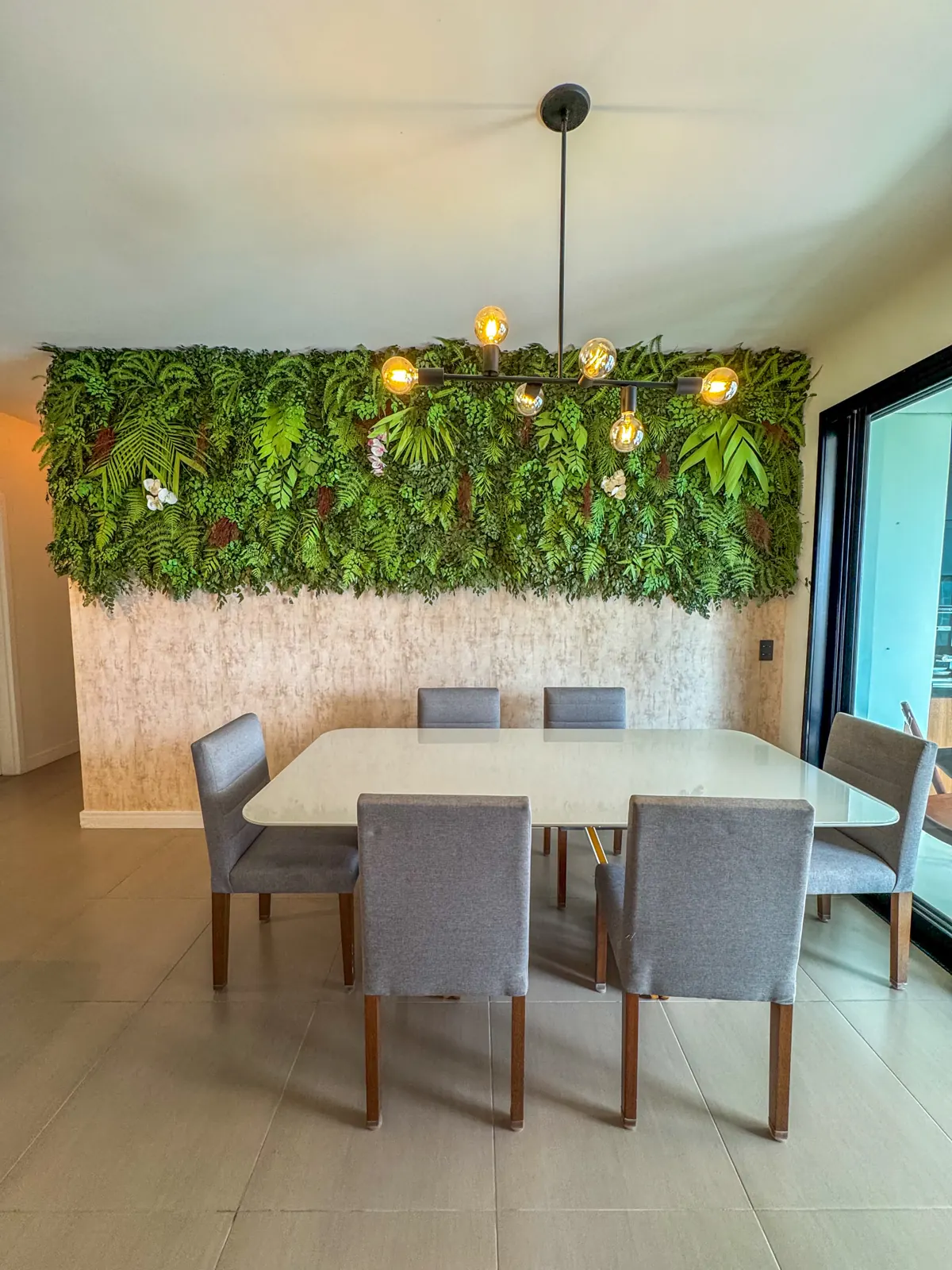 Mesa de jantar com jardim vertical e pendente dourado